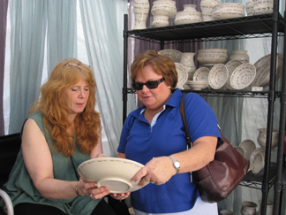 Leslie Reich of Pottery Mountain, Woodstock NY, shows her work to a customer at the 22nd Festival of the Arts in Delray Beach, Florida.